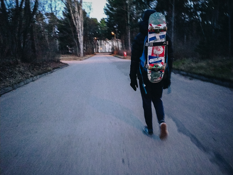 boy with skateboard walking on the road